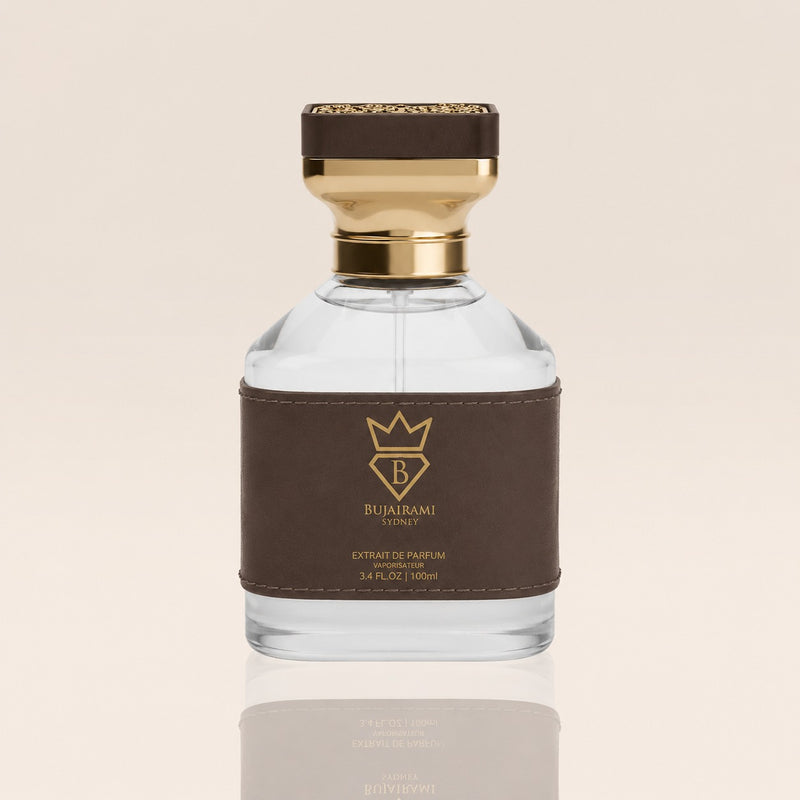 A clear glass bottle of Bujairami Euphoric Parfum with a dark brown leather label and a gold cap, set against a light beige background with a soft reflection below.